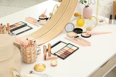 Photo of Makeup room. Dressing table with mirror, different beauty products and jewelry indoors, closeup