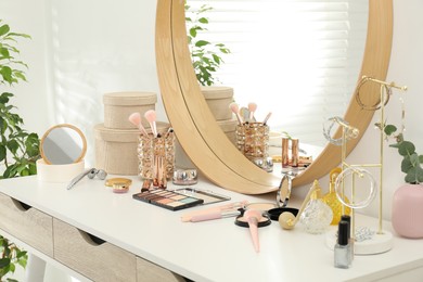 Photo of Makeup room. Dressing table with mirror, different beauty products and jewelry indoors