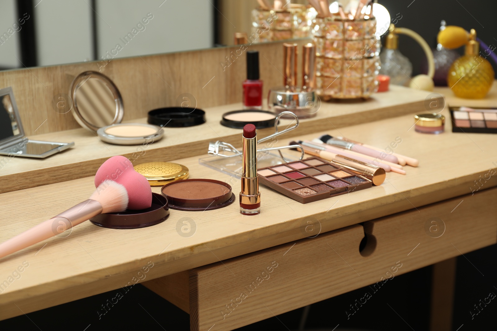 Photo of Makeup room. Different cosmetic products on wooden dressing table indoors, closeup