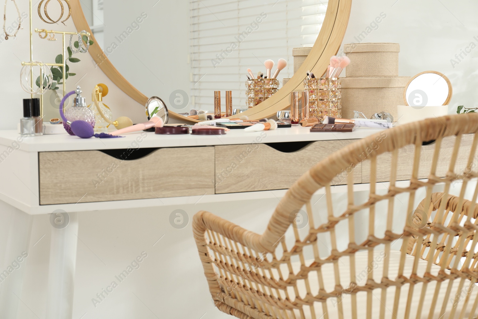 Photo of Makeup room. Dressing table with mirror, different beauty products, jewelry and chair indoors