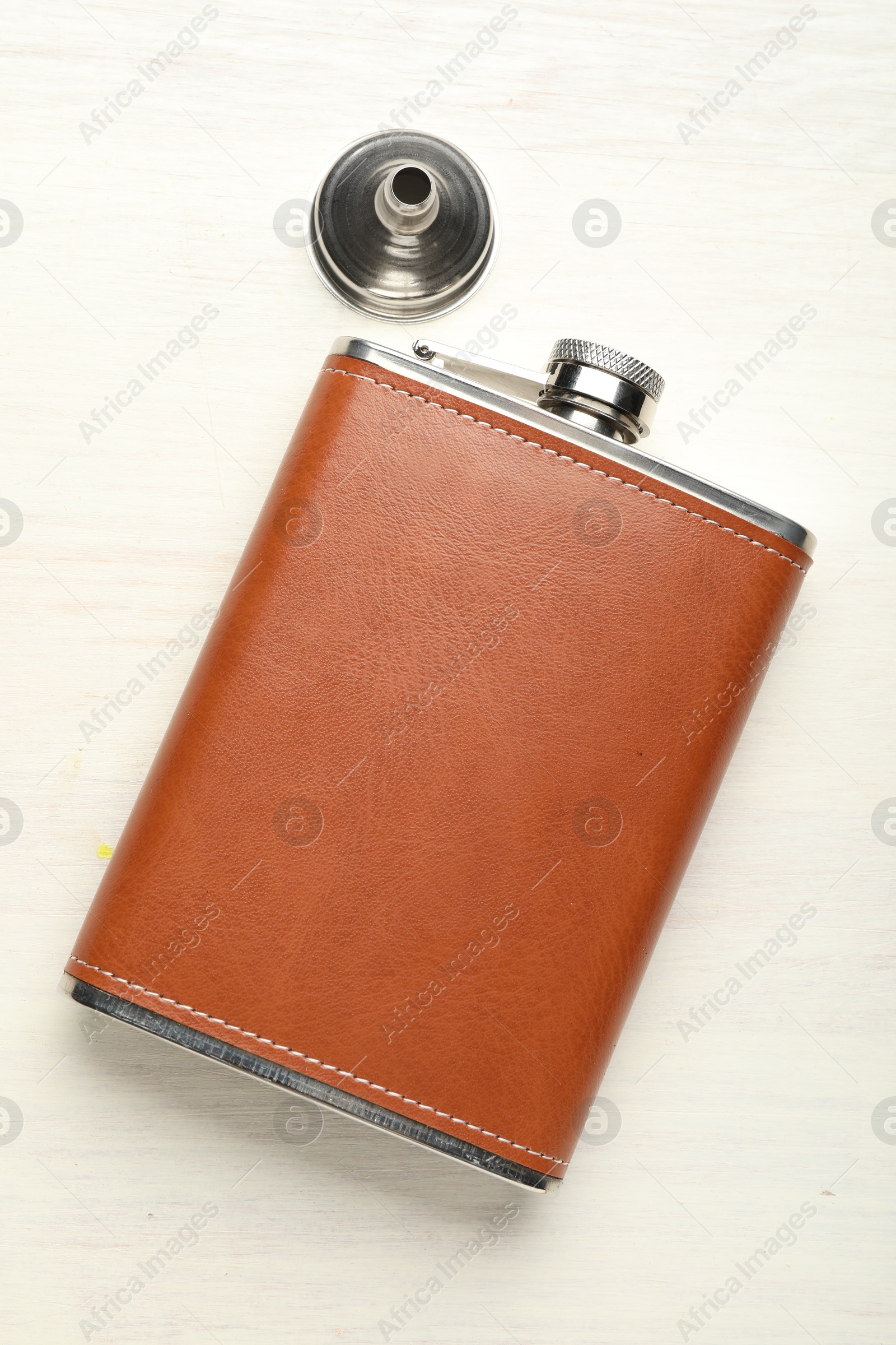 Photo of Hip flask and funnel on light wooden table, flat lay