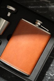 Photo of Hip flask, cup and funnel in package on dark table, top view