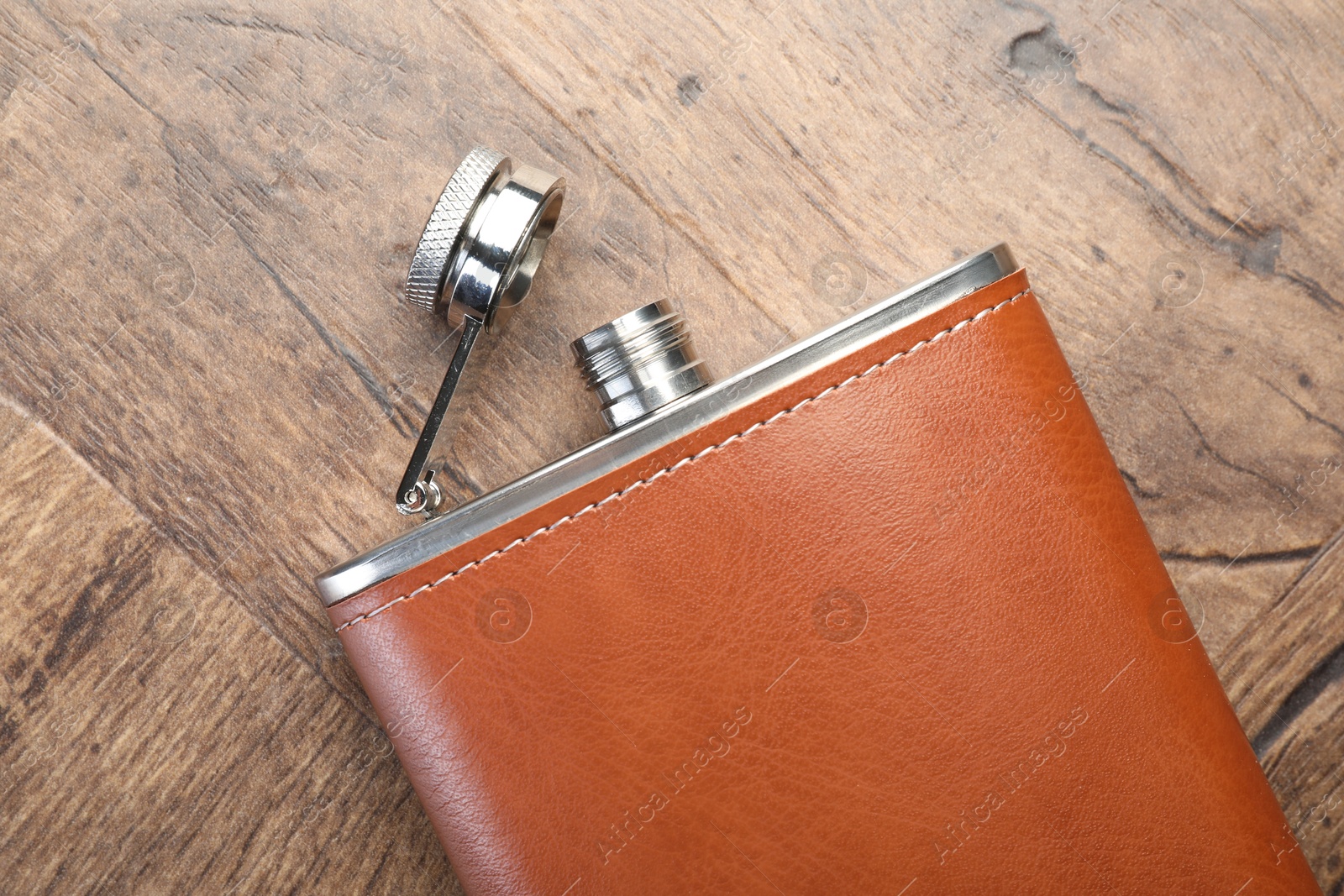 Photo of One hip flask on wooden table, top view