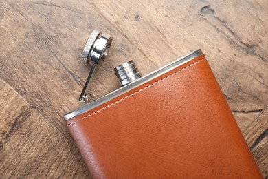 Photo of One hip flask on wooden table, top view