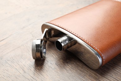 Photo of One hip flask on wooden table, closeup