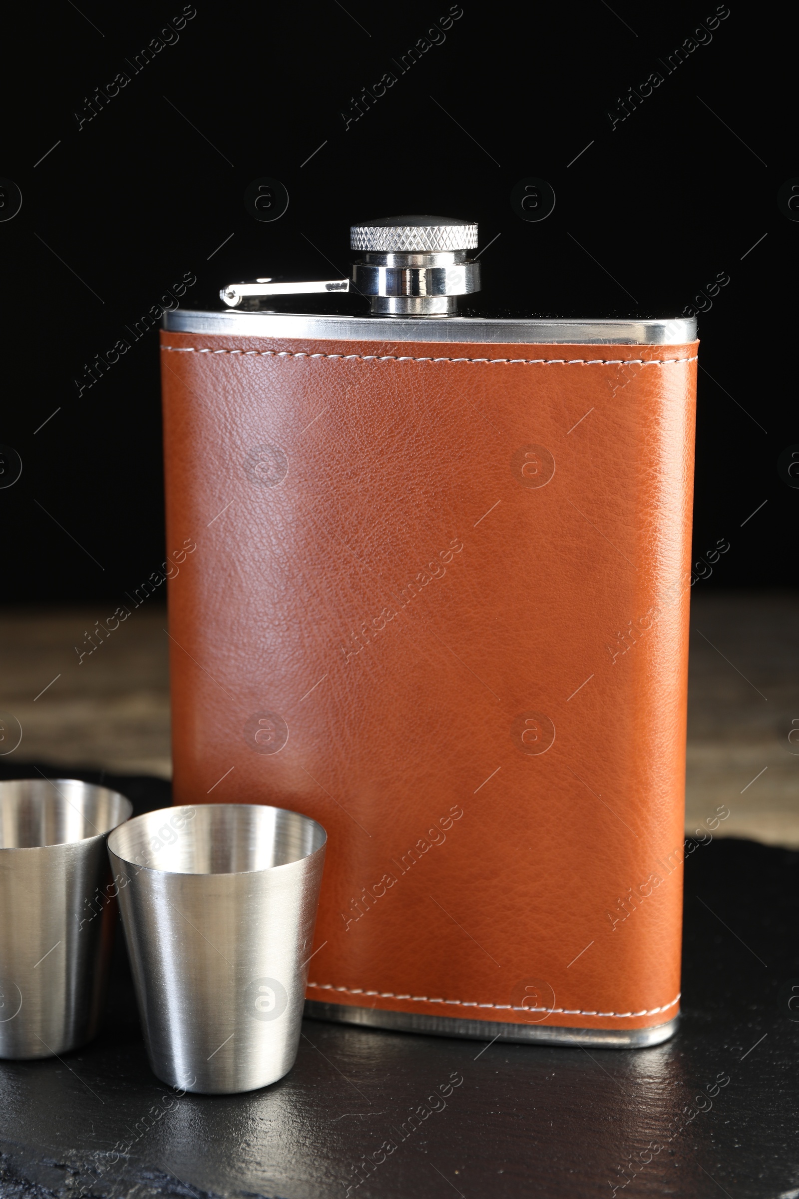 Photo of Hip flask and cups on table, closeup