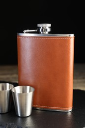 Photo of Hip flask and cups on table, closeup