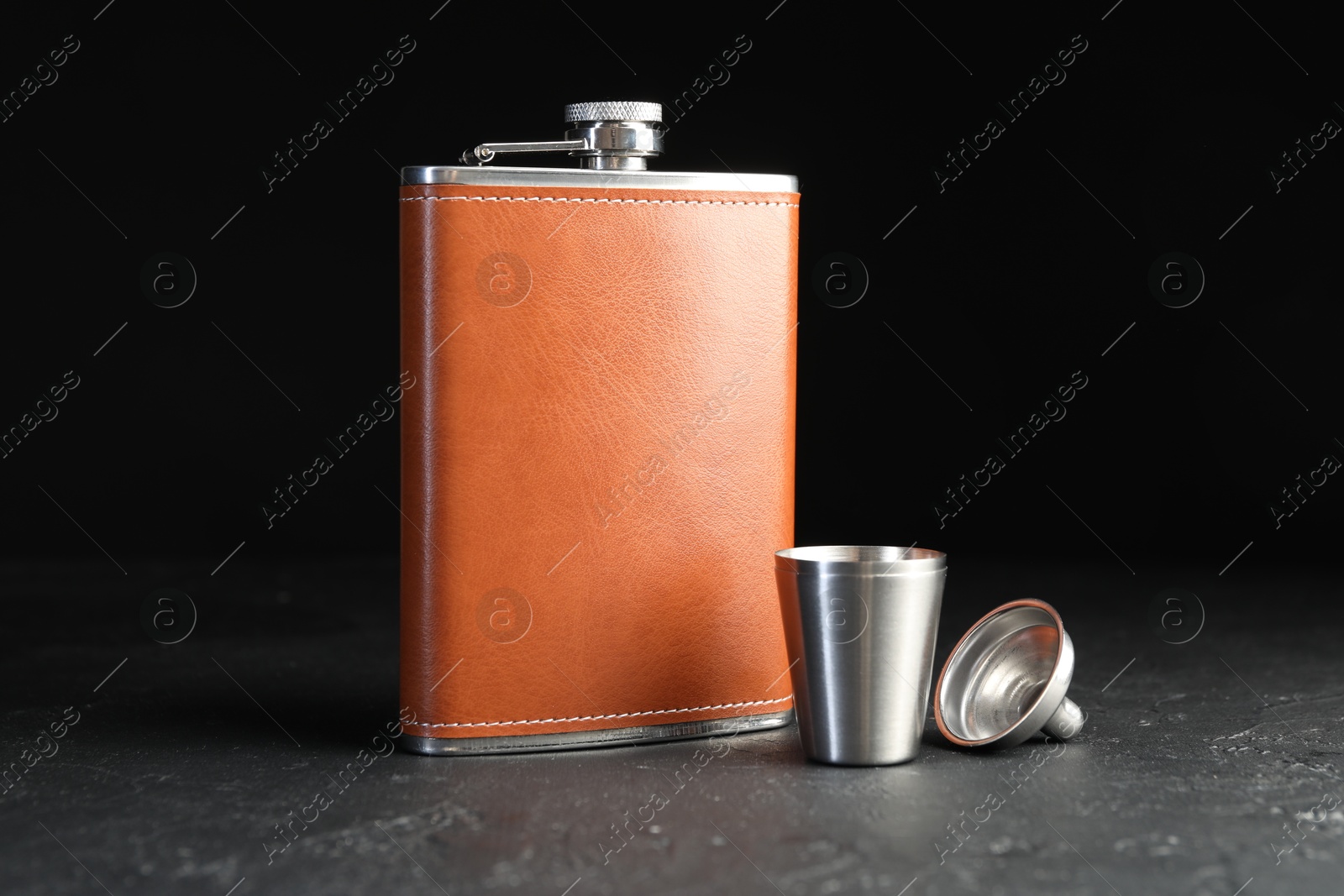 Photo of Hip flask, cup and funnel on black table