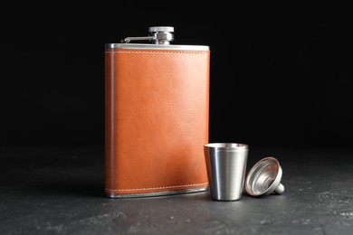 Photo of Hip flask, cup and funnel on black table