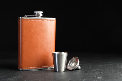 Photo of Hip flask, cup and funnel on black table, space for text