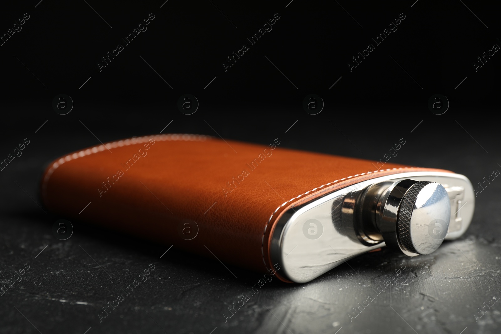 Photo of One hip flask on black table, closeup