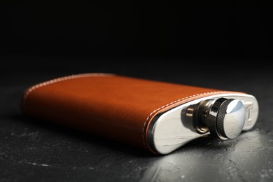 Photo of One hip flask on black table, closeup