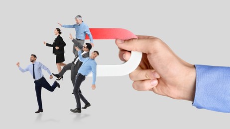 Image of Man with horseshoe magnet in his hand attracting business people on grey background, closeup