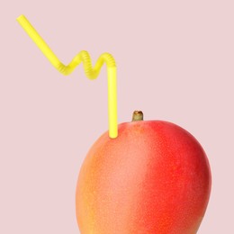 Image of Ripe mango with drinking straw on pink grey background. Organic juice or freshly made smoothie concept