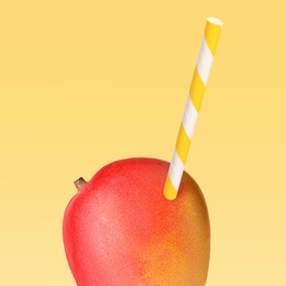 Image of Ripe mango with drinking straw on yellow background. Organic juice or freshly made smoothie concept