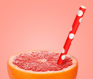 Image of Half of grapefruit with drinking straw on pink background. Organic juice or freshly made smoothie concept