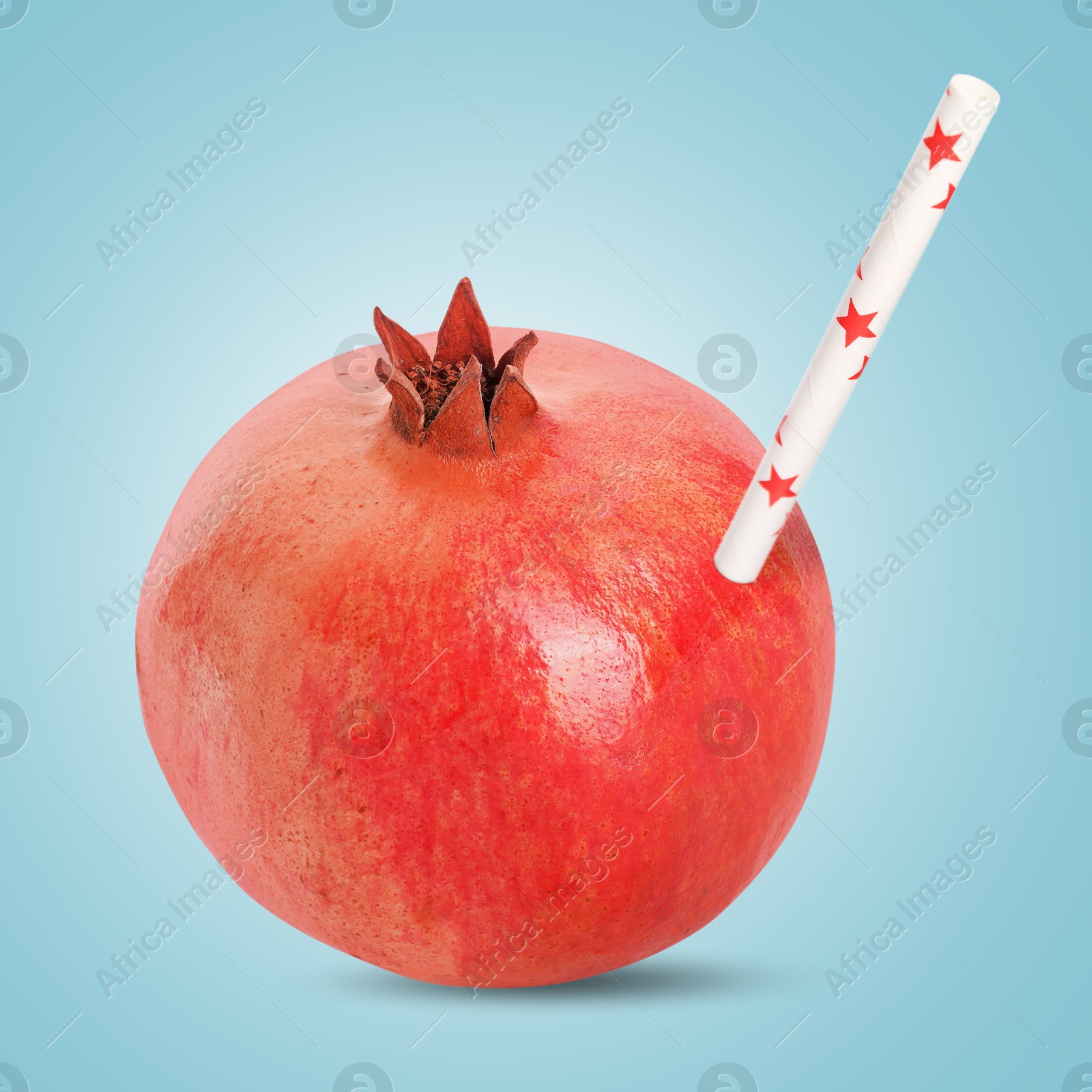 Image of Ripe pomegranate with drinking straw on light blue background. Organic juice or freshly made smoothie concept