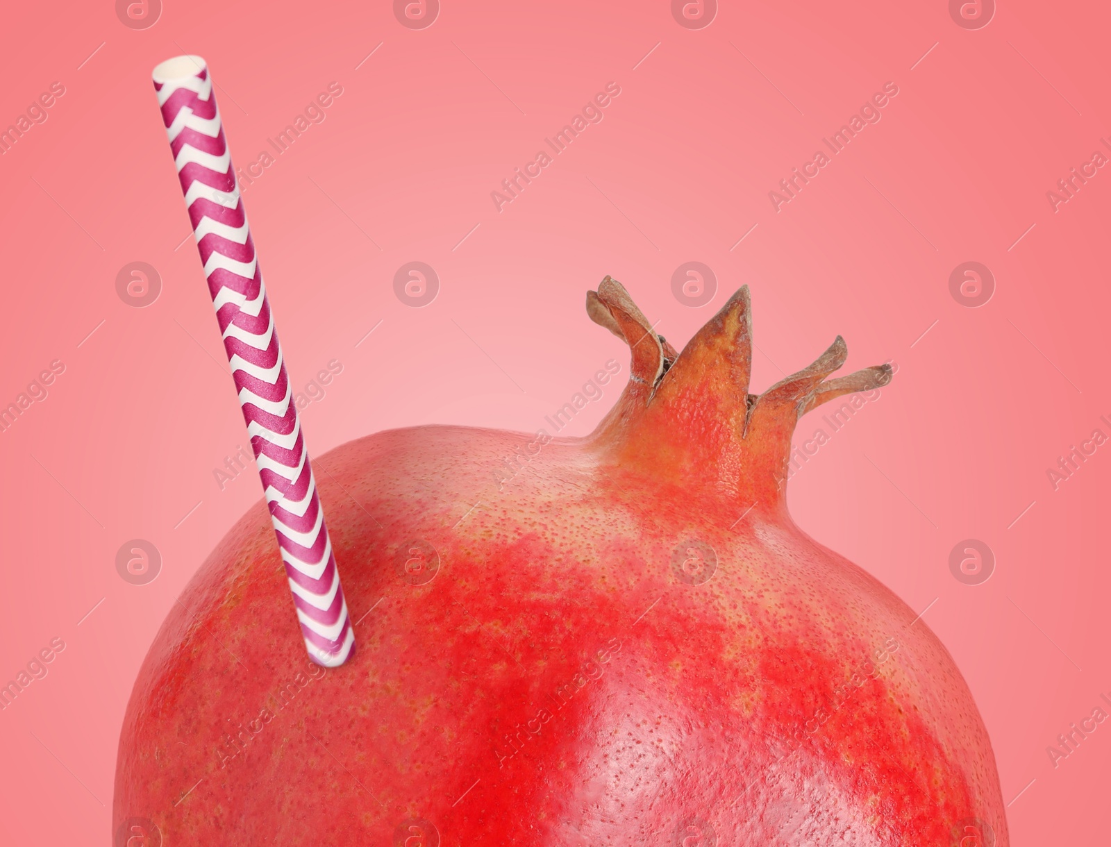 Image of Ripe pomegranate with drinking straw on pink background. Organic juice or freshly made smoothie concept