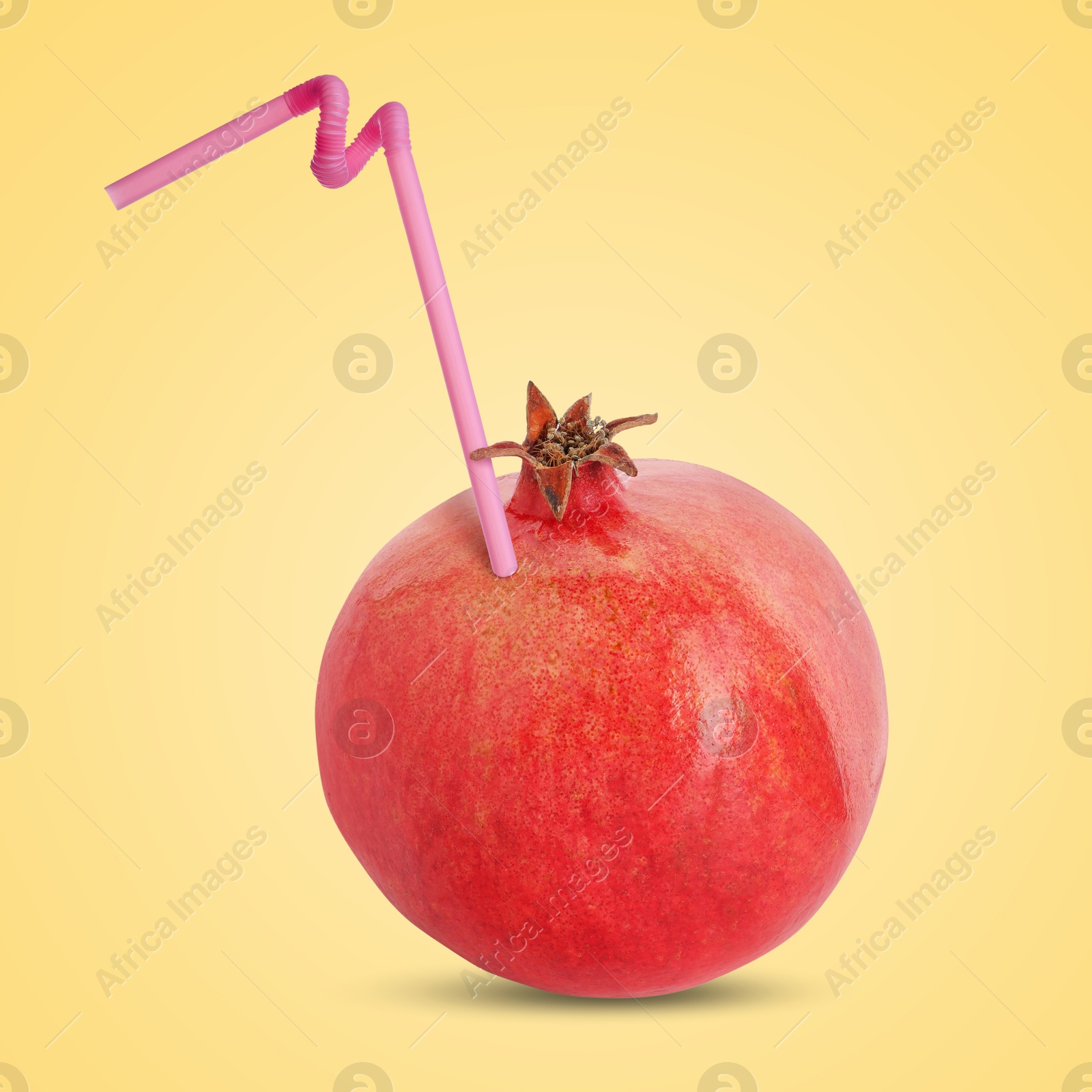 Image of Ripe pomegranate with drinking straw on yellow background. Organic juice or freshly made smoothie concept