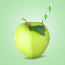 Image of Ripe apple with drinking straw on light green background. Organic juice or freshly made smoothie concept