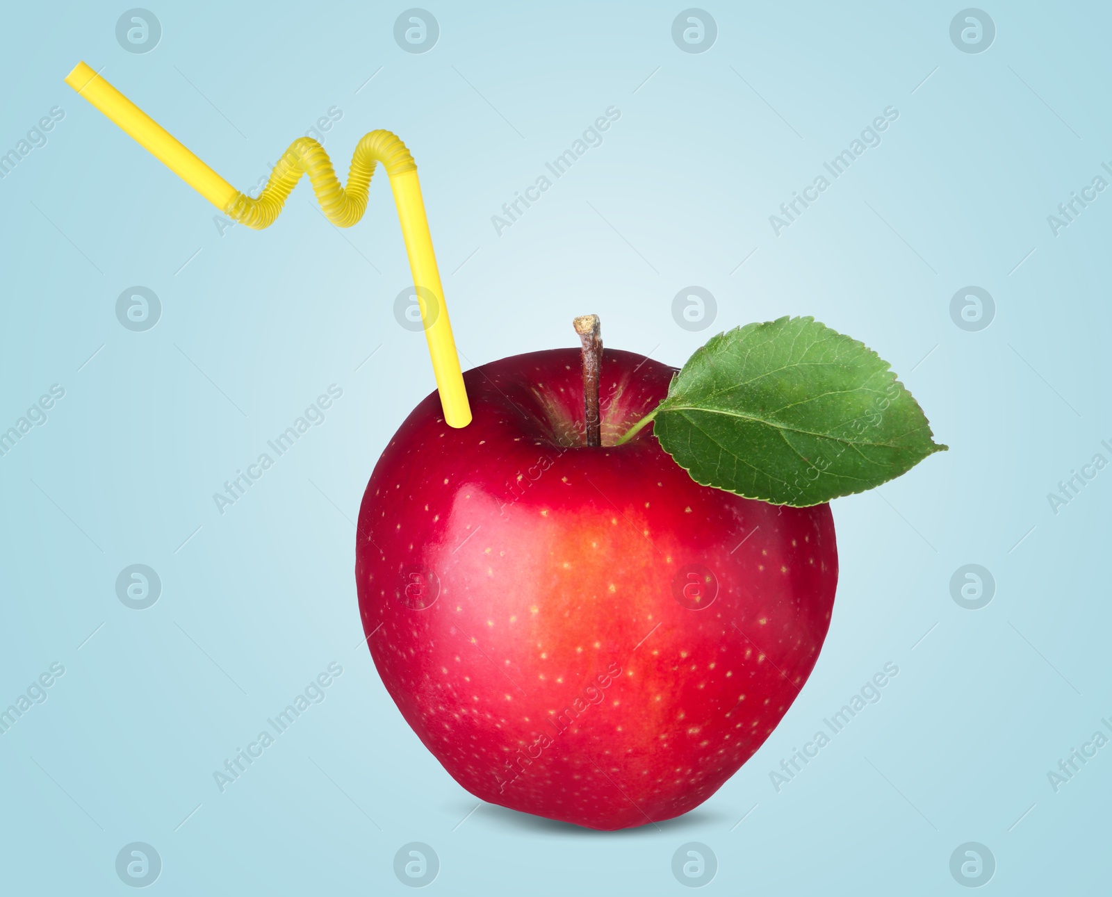 Image of Ripe red apple with drinking straw on light blue background. Organic juice or freshly made smoothie concept