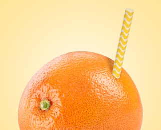 Image of Ripe grapefruit with drinking straw on yellow background. Organic juice or freshly made smoothie concept