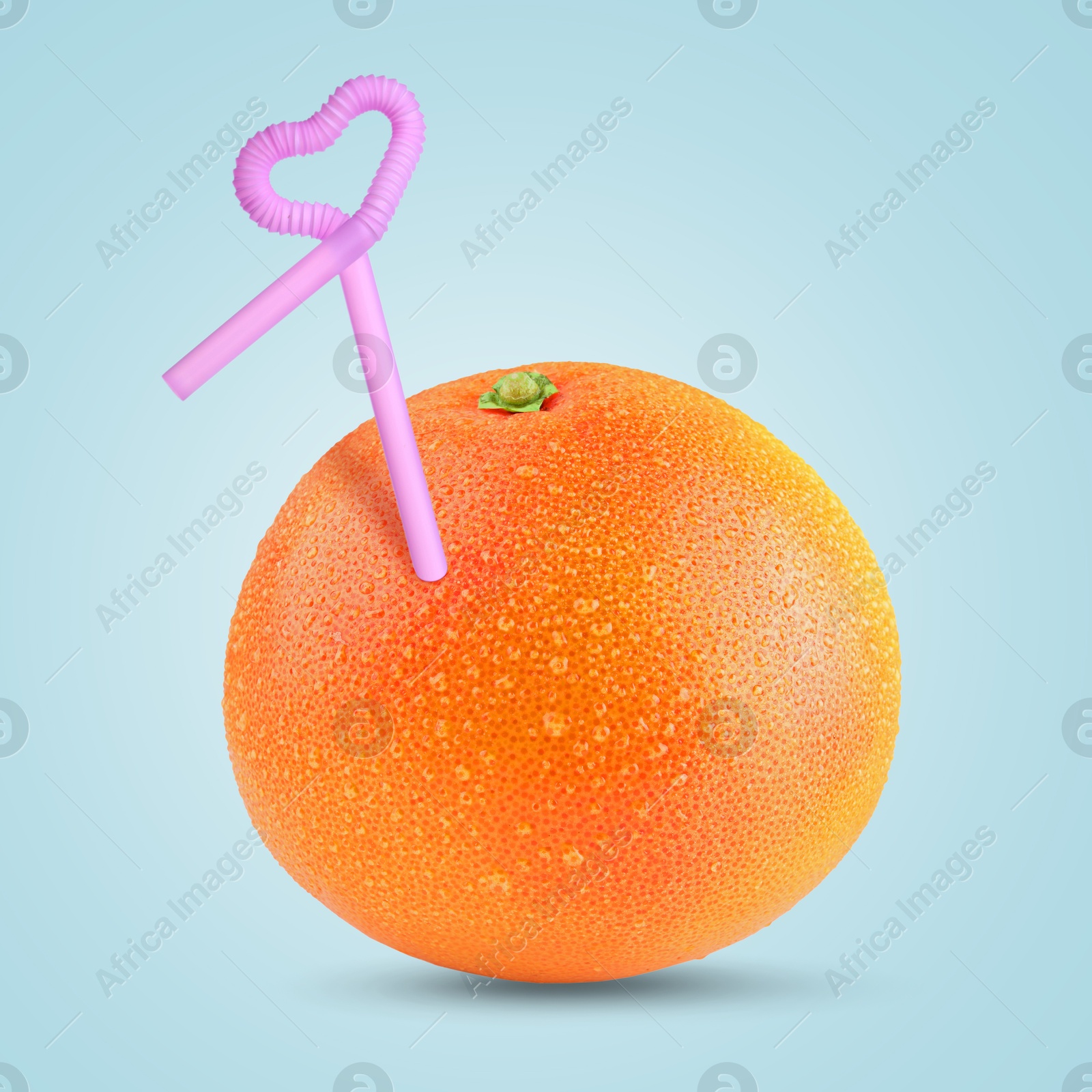 Image of Ripe grapefruit with drinking straw on light blue background. Organic juice or freshly made smoothie concept