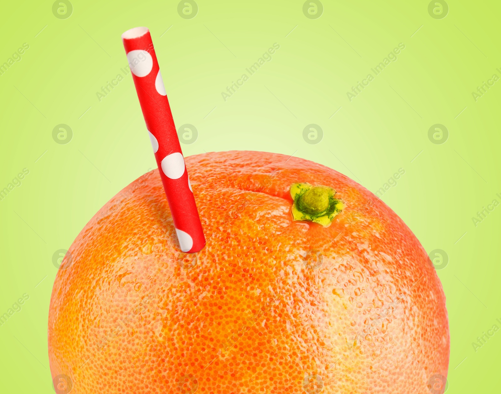 Image of Ripe grapefruit with drinking straw on light green background. Organic juice or freshly made smoothie concept