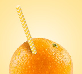 Image of Ripe orange with drinking straw on yellow background. Organic juice or freshly made smoothie concept