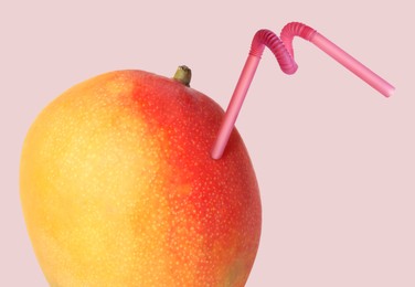 Image of Ripe mango with drinking straw on pink grey background. Organic juice or freshly made smoothie concept