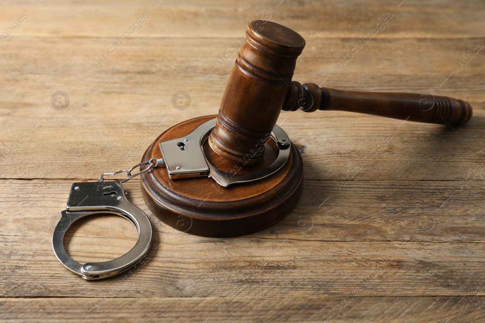 Photo of Handcuffs and judge's gavel on wooden table