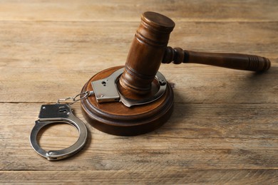 Photo of Handcuffs and judge's gavel on wooden table