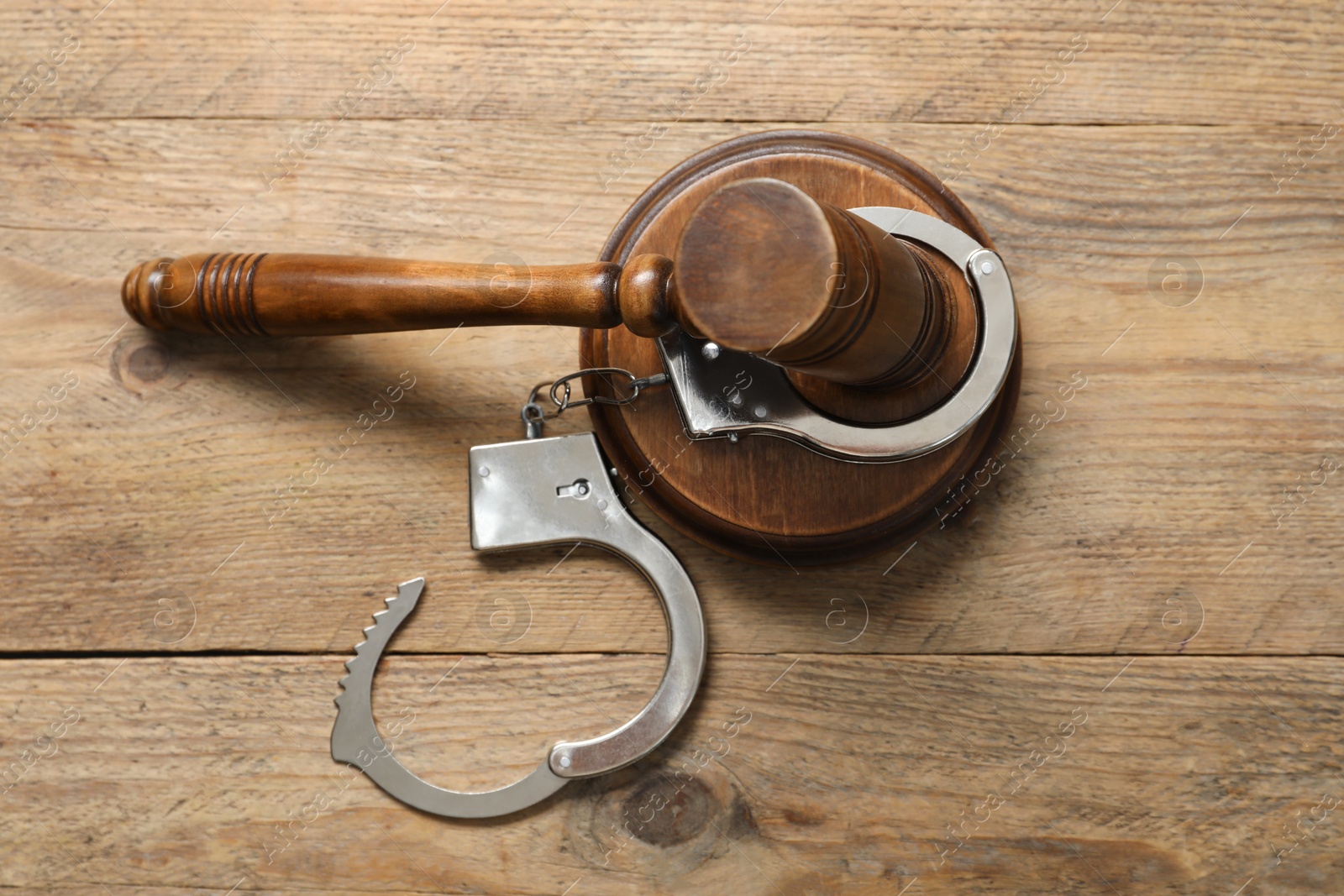 Photo of Handcuffs and judge's gavel on wooden table, flat lay