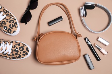 Photo of Stylish accessories and makeup products on brown background, flat lay