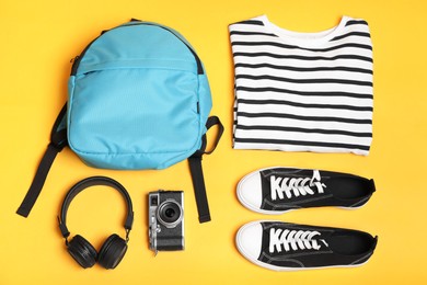 Photo of Stylish outfit with backpack on yellow background, flat lay