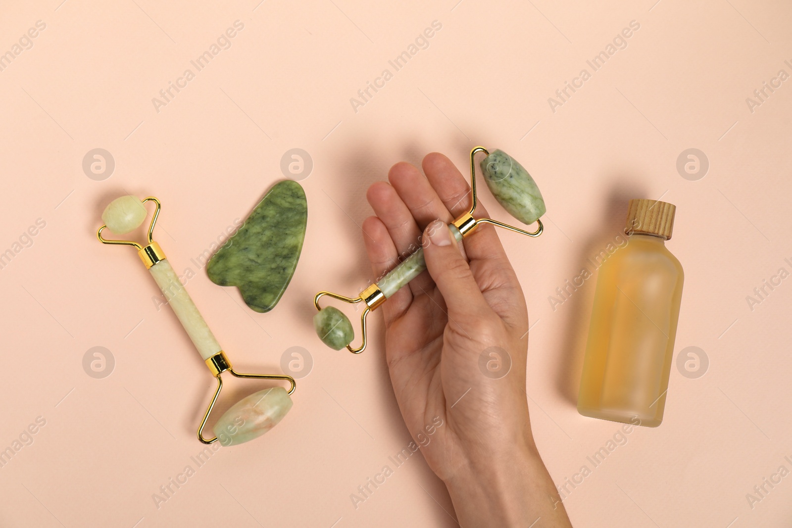 Photo of Woman with face rollers, gua sha tool and cosmetic product on beige background, top view