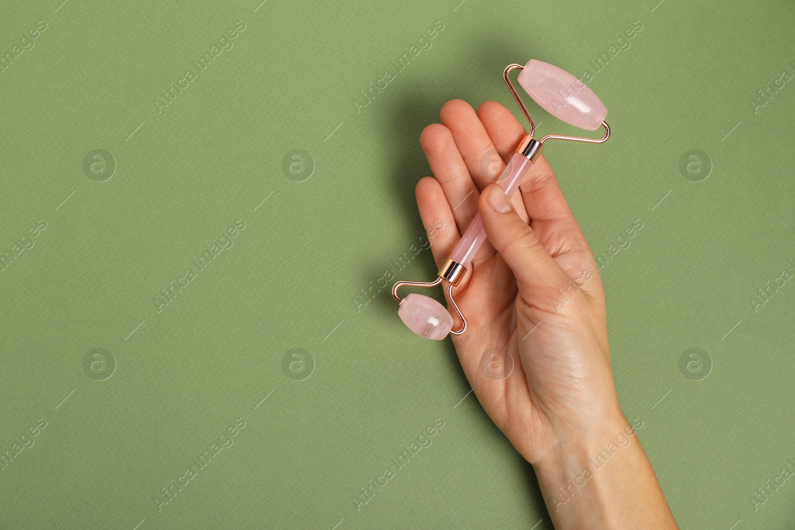 Photo of Woman with face roller on green background, top view. Space for text