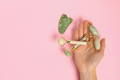 Photo of Woman with face rollers and gua sha tool on pink background, top view. Space for text