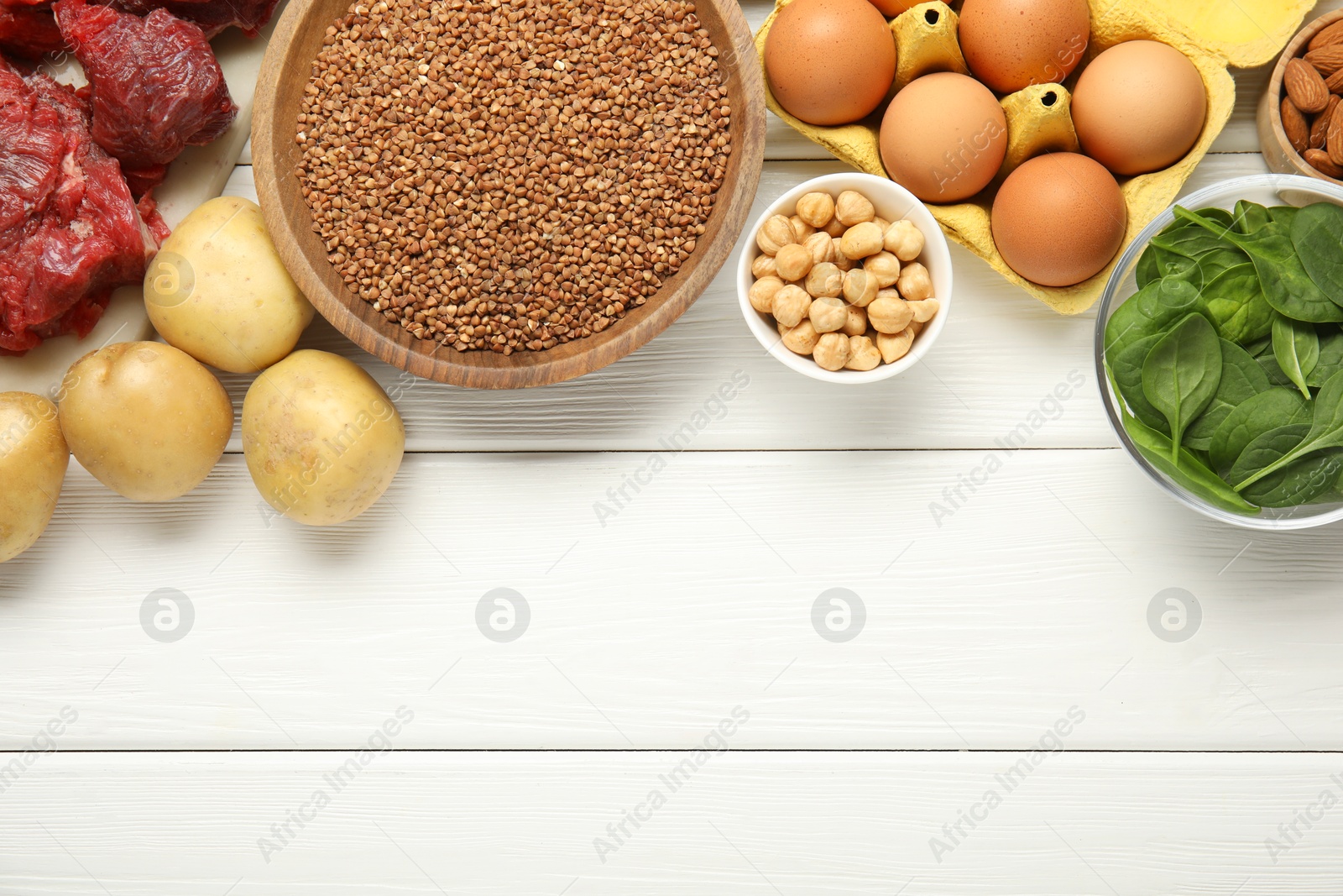 Photo of Different products rich in iron on white wooden table, flat lay. Space for text