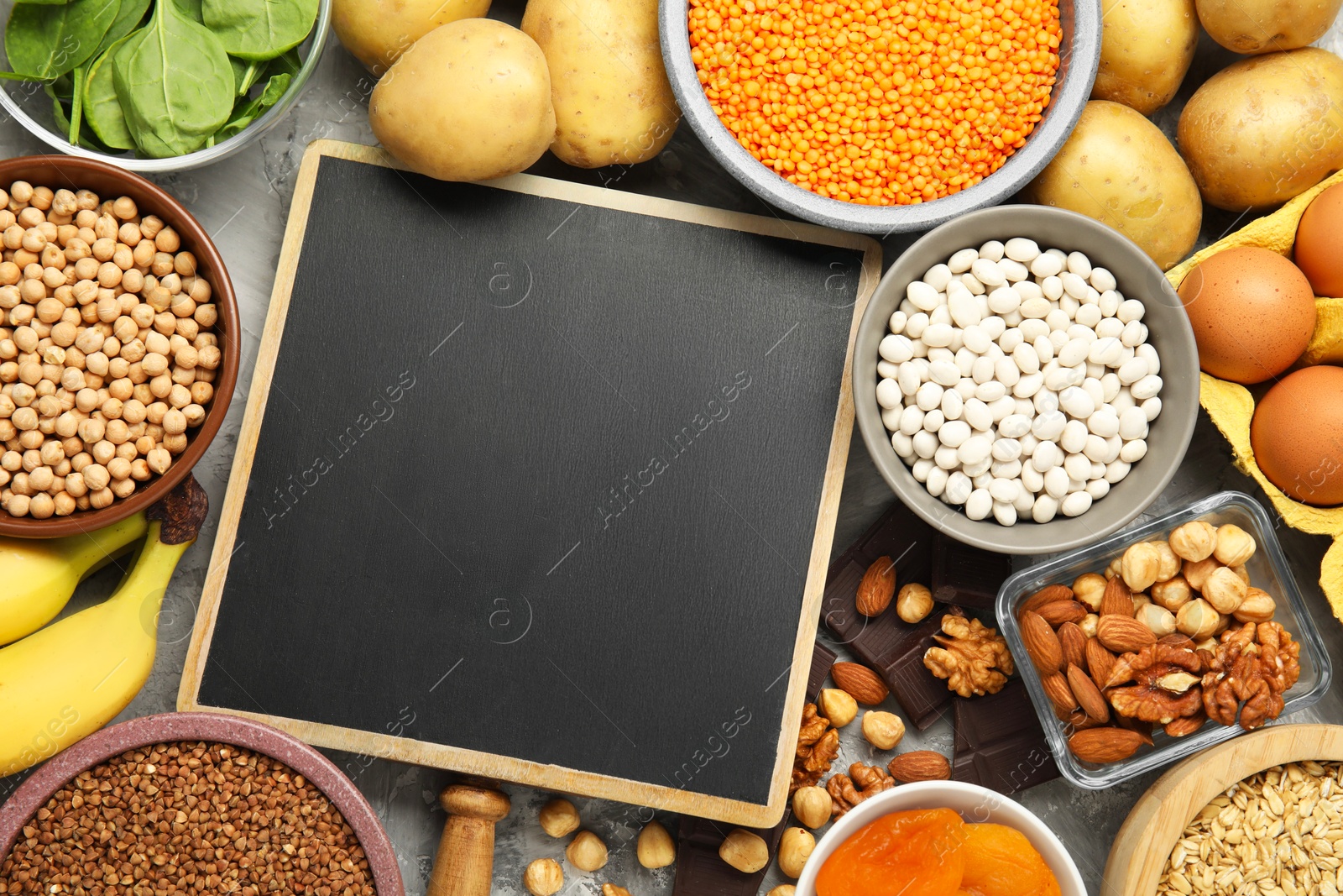 Photo of Diet plan for anemia. Different products rich in iron and small chalkboard on grey table, flat lay. Space for text