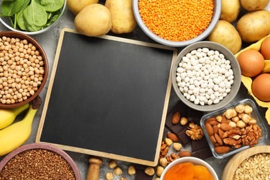 Photo of Diet plan for anemia. Different products rich in iron and small chalkboard on grey table, flat lay. Space for text