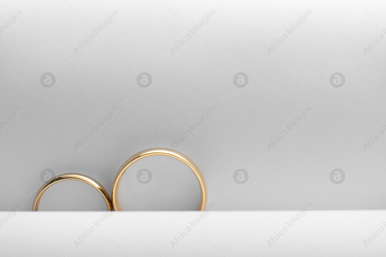 Photo of Beautiful golden wedding rings on light background, top view. Space for text