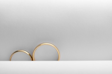 Beautiful golden wedding rings on light background, top view. Space for text