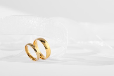 Beautiful golden wedding rings and ribbon on white background