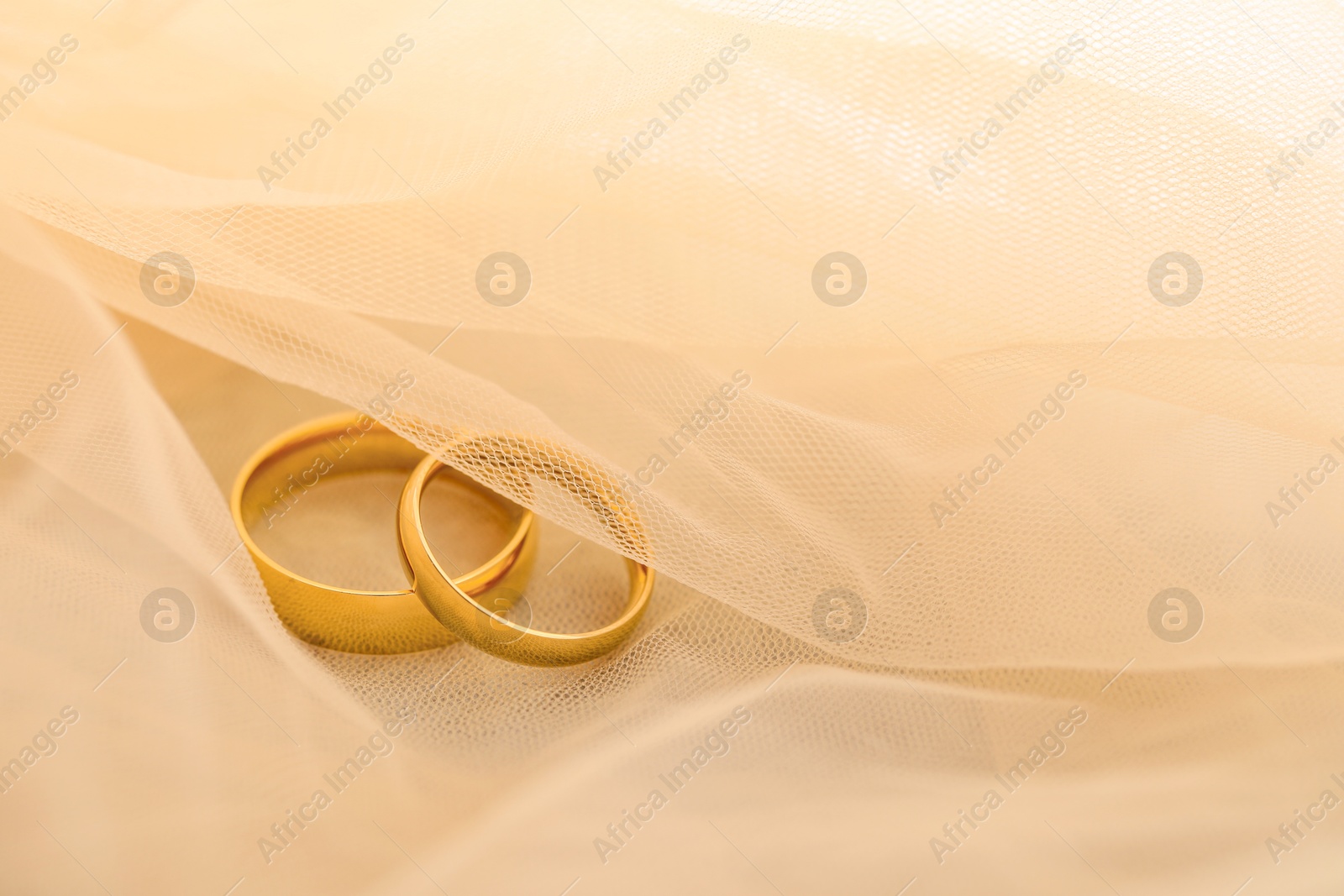 Photo of Beautiful golden wedding rings on beige fabric, space for text