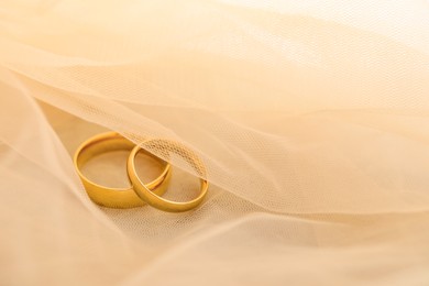 Photo of Beautiful golden wedding rings on beige fabric, space for text