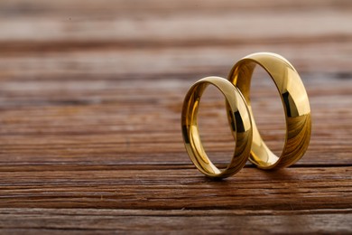 Beautiful golden wedding rings on wooden background, space for text