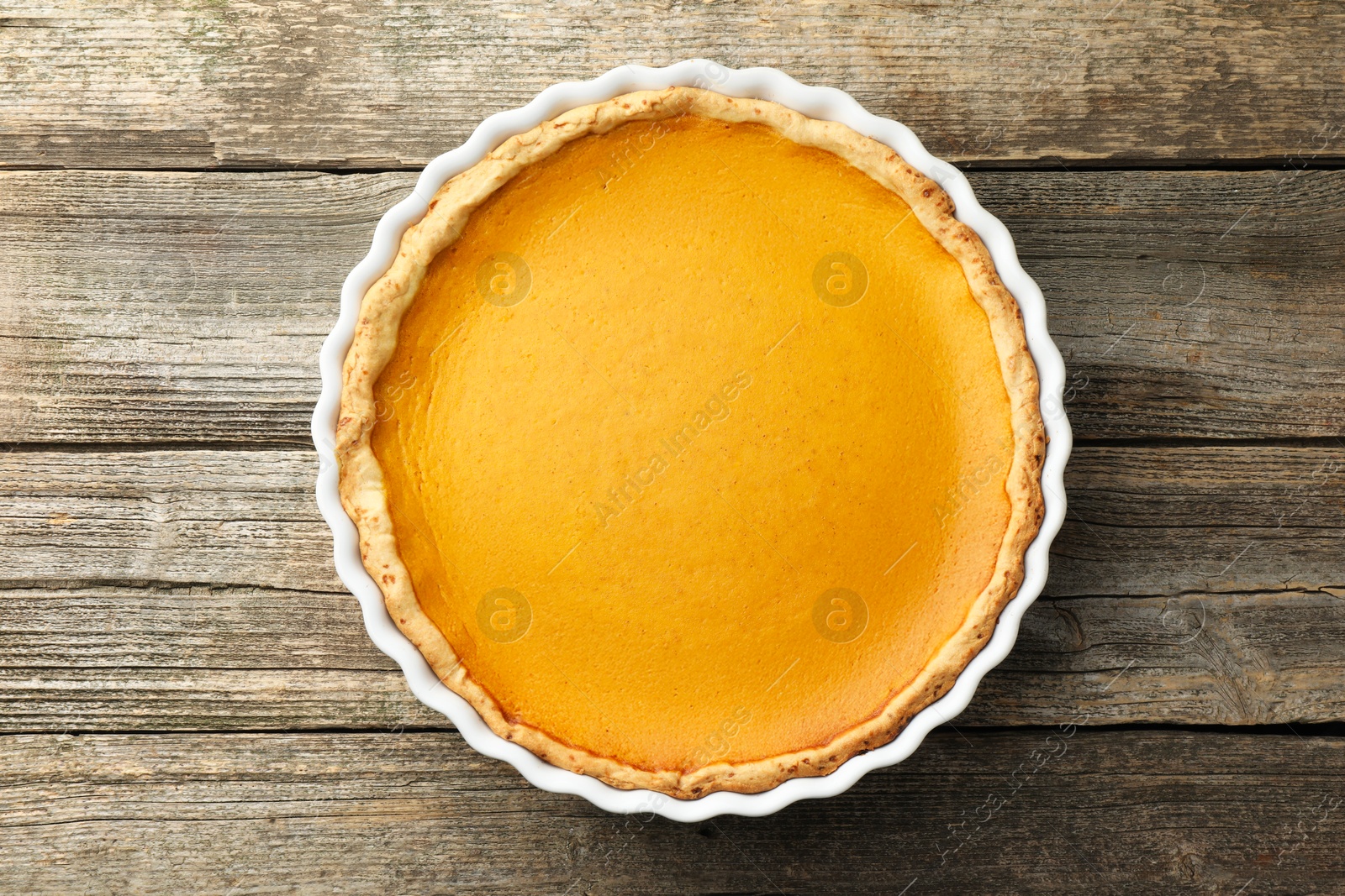 Photo of Tasty homemade pumpkin pie in baking dish on wooden table, top view