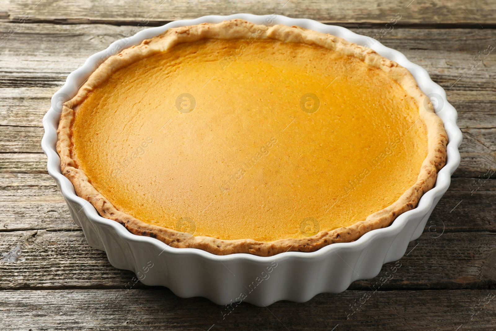 Photo of Tasty homemade pumpkin pie in baking dish on wooden table, closeup