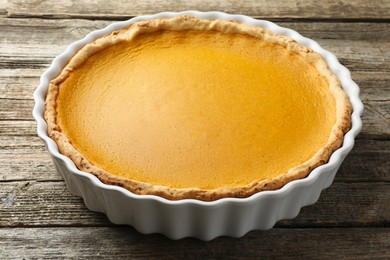 Photo of Tasty homemade pumpkin pie in baking dish on wooden table, closeup